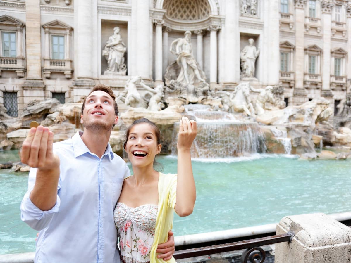 couple throwing coins in trevi fountain