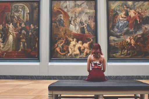 girl admiring paintings inside the Louvre